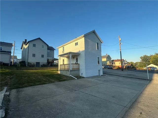 a view of a big house with a big yard and large trees