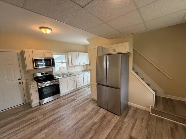 a kitchen with granite countertop stainless steel appliances a refrigerator a stove top oven and wooden floor