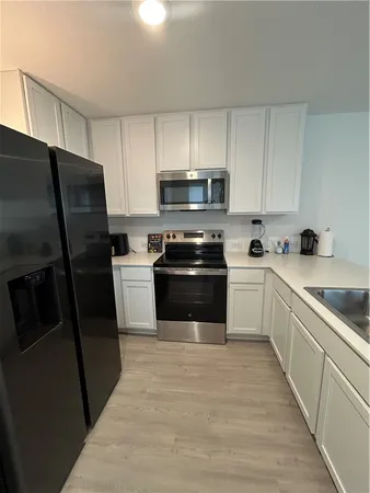 a kitchen with a refrigerator a sink a stove a microwave and cabinets