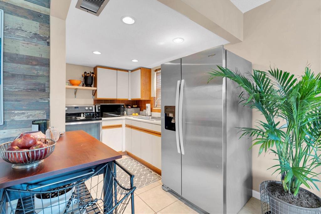 8800 Blind Pass Road, Unit 10 St. Pete Beach, FL 33706 - Photo 9 of 24 a kitchen with stainless steel appliances granite countertop a refrigerator a stove and a wooden floors