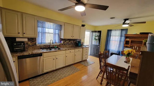 a kitchen with stainless steel appliances granite countertop a sink a stove a refrigerator cabinets and dining table