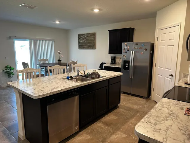 a kitchen with stainless steel appliances granite countertop a sink a refrigerator and a refrigerator