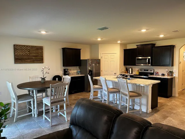 a living room with furniture a flat screen tv and kitchen view