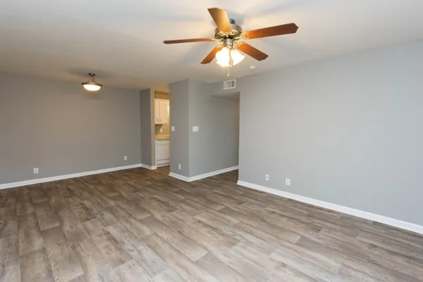 an empty room with wooden floor and a ceiling fan