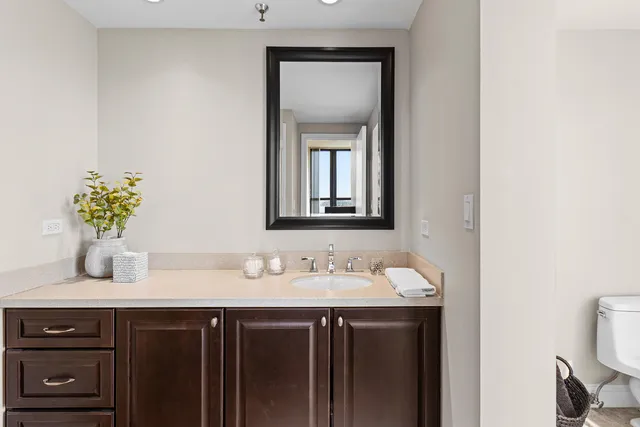 a bathroom with a toilet sink vanity and mirror