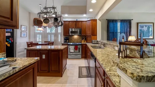 a kitchen with kitchen island granite countertop a sink stove and refrigerator