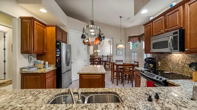 a kitchen with stainless steel appliances granite countertop a sink dishwasher stove refrigerator and cabinets