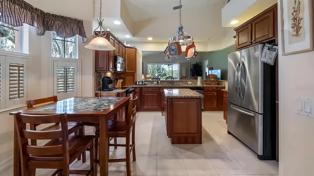 a kitchen with stainless steel appliances granite countertop a sink a stove a refrigerator a dining table and chairs