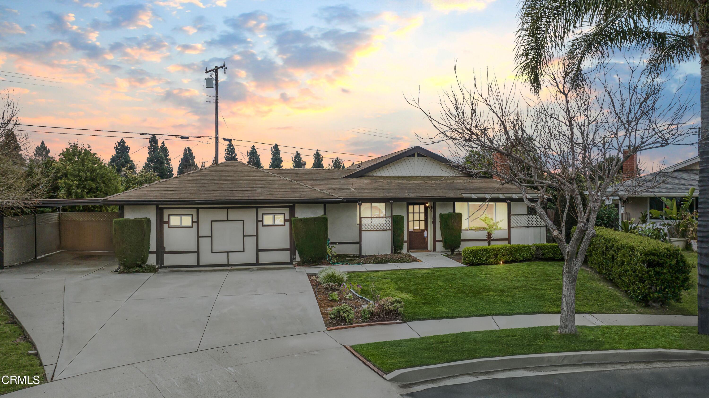 a front view of a house with a garden and trees