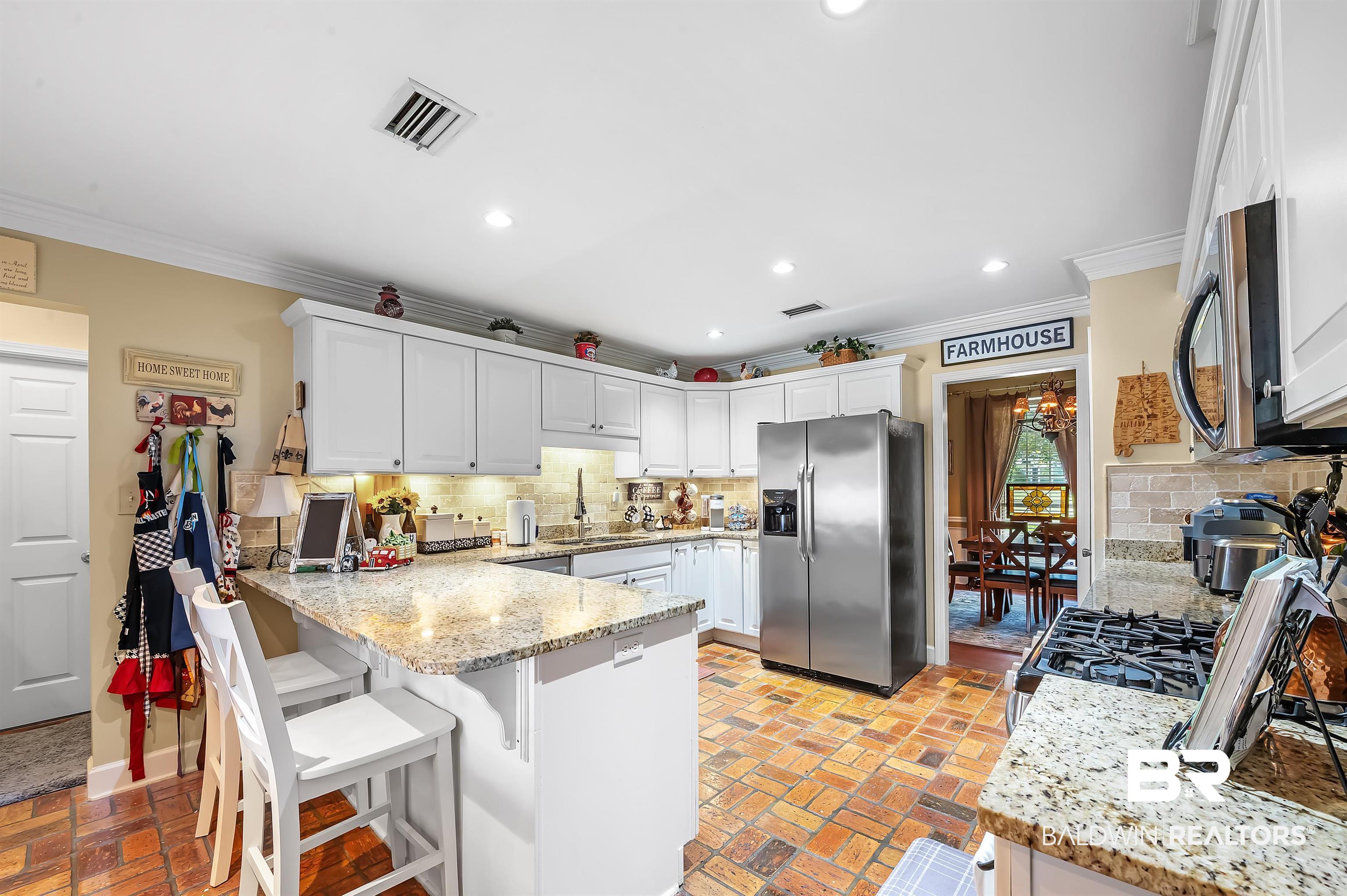 9901 Glover Court Fairhope, AL 36532 - Photo 12 of 52 Kitchen with stainless steel appliances, white cabinets, light stone counters, and backsplash