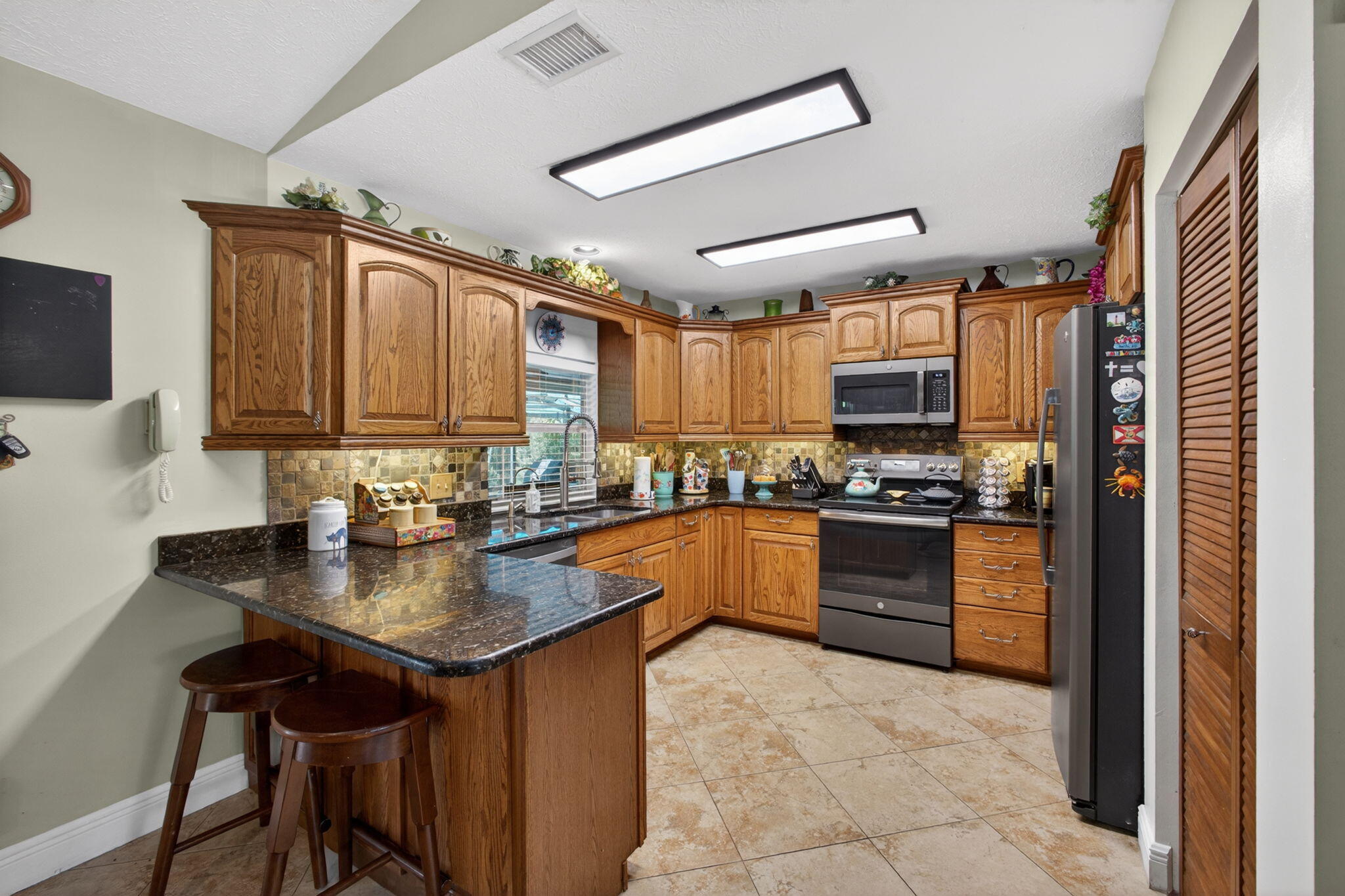 12558 165th Road North Jupiter, FL 33478 - Photo 21 of 67 a kitchen with stainless steel appliances granite countertop a stove refrigerator sink and cabinets