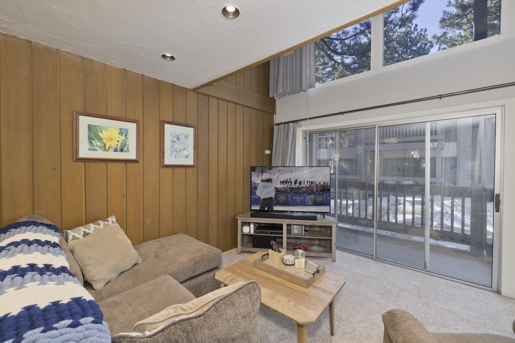 286 Old Mammoth Road, Unit 37 Mammoth Lakes, CA 93546 - Photo 7 of 33 Carpeted living room featuring wood walls and a high ceiling