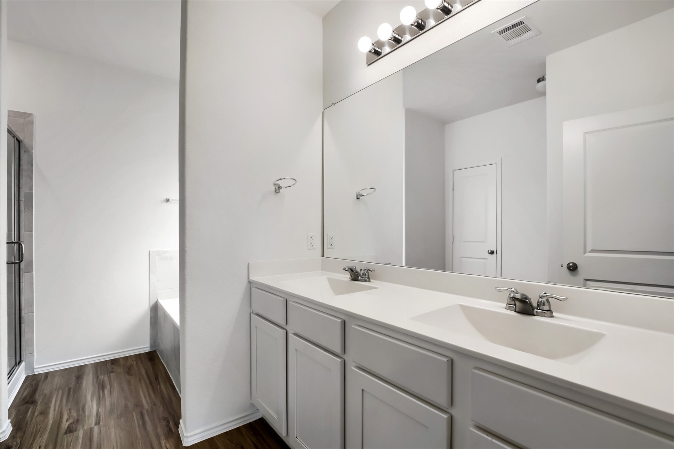 721 Mallow Road Leander, TX 78641 - Photo 13 of 22 Bathroom featuring a double vanity with white cabinets and countertops, a large mirror, a shower with a clear glass door, and a separate bathtub