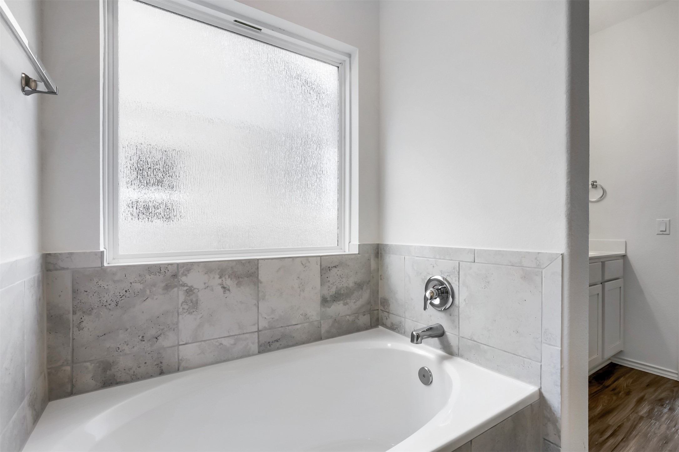 721 Mallow Road Leander, TX 78641 - Photo 14 of 22 A bright bathroom featuring a built-in bathtub with chrome fixtures, a tiled surround, and a frosted window above