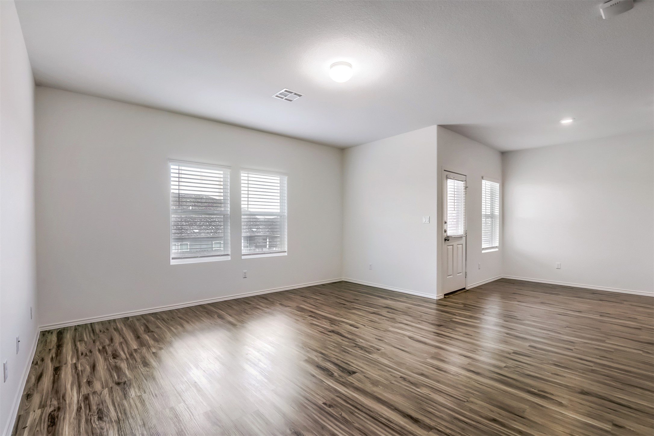 721 Mallow Road Leander, TX 78641 - Photo 4 of 22 Spacious living area featuring hardwood flooring, white walls, and multiple windows with blinds providing natural light