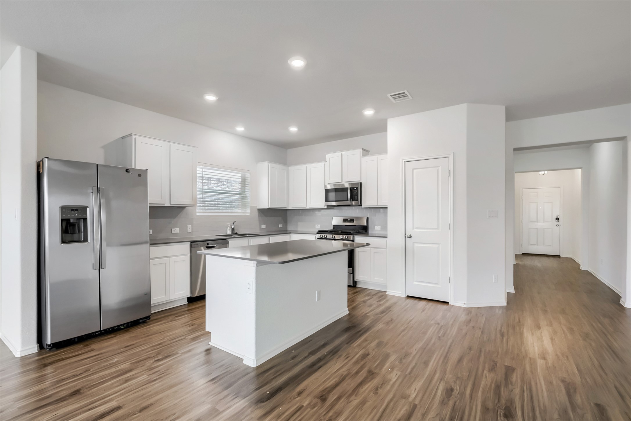 721 Mallow Road Leander, TX 78641 - Photo 9 of 22 The kitchen features white cabinetry, stainless steel appliances, and a central island with a contrasting countertop