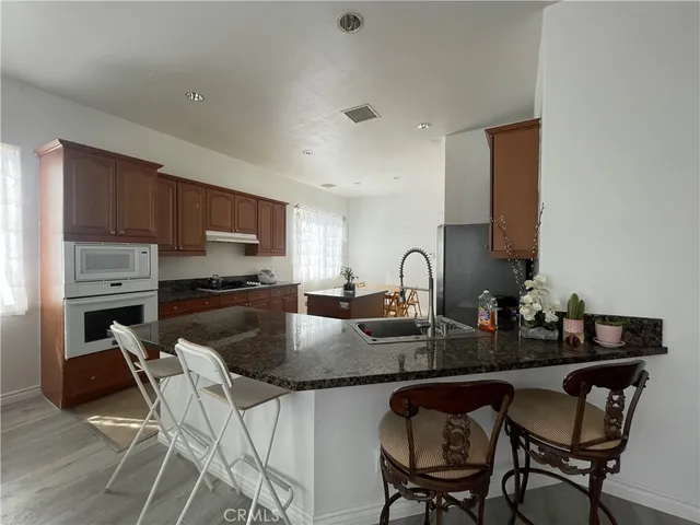 a kitchen with granite countertop a table chairs stove microwave and cabinets