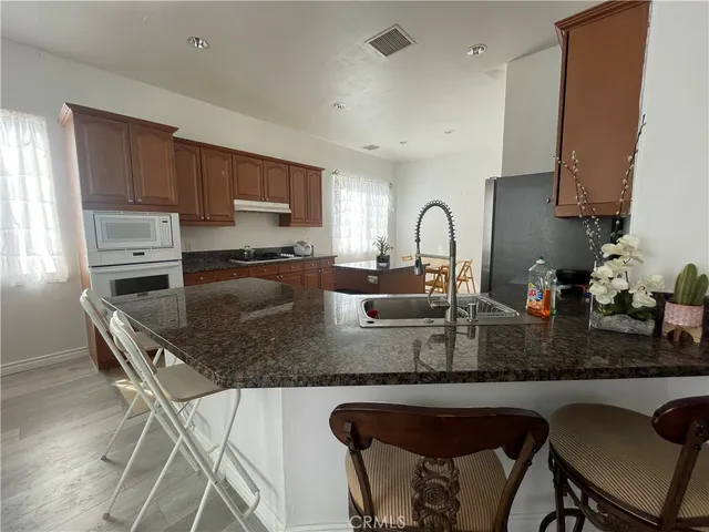 a kitchen with stainless steel appliances granite countertop a table chairs sink and cabinets