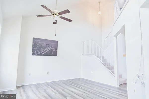 a view of a hallway with wooden floor and a ceiling fan