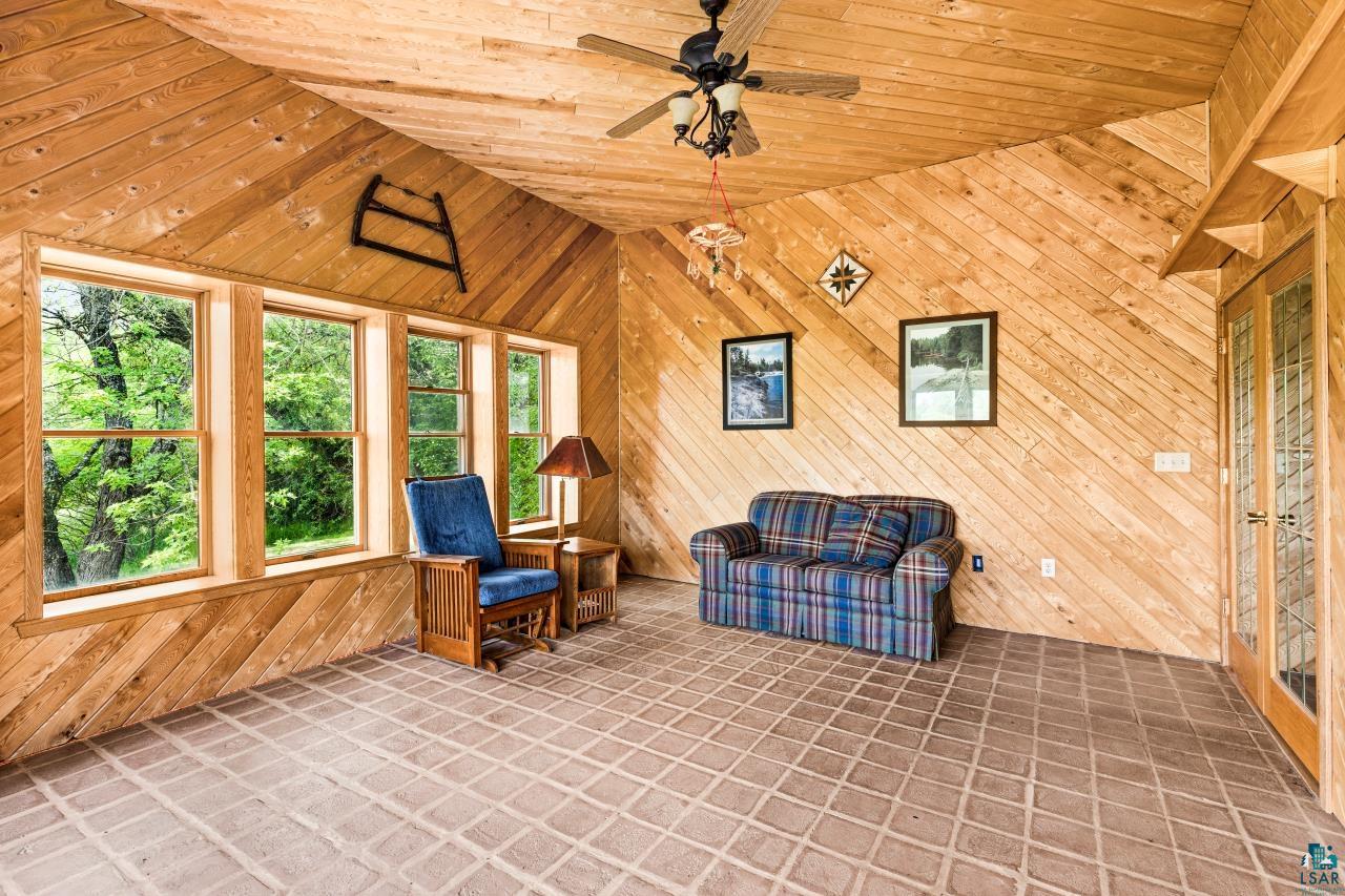 4800 Tower Road Moose Lake, MN 55767 - Photo 23 of 83 Sunroom featuring extensive wood plank paneling on walls and ceiling, diagonal floor tiling, multiple windows overlooking lush greenery, a ceiling fan, and French doors with decorative glass inserts