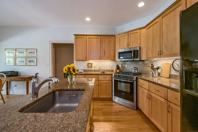 a kitchen with kitchen island granite countertop a sink stove and refrigerator