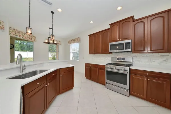 a kitchen with stainless steel appliances granite countertop a sink a stove and a wooden cabinets
