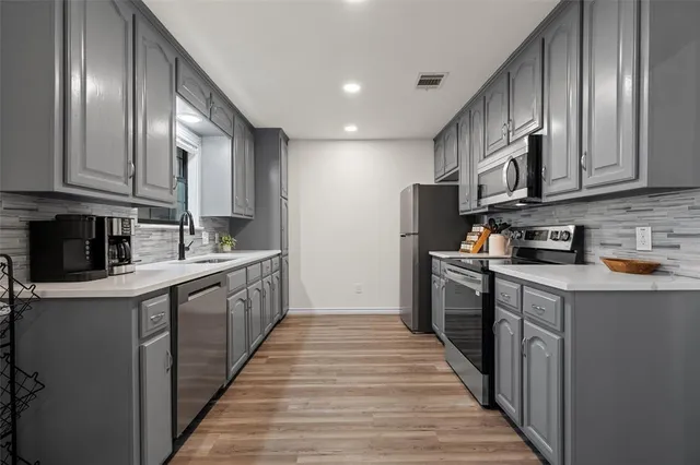 a kitchen with stainless steel appliances granite countertop a refrigerator a stove top oven a sink and dishwasher