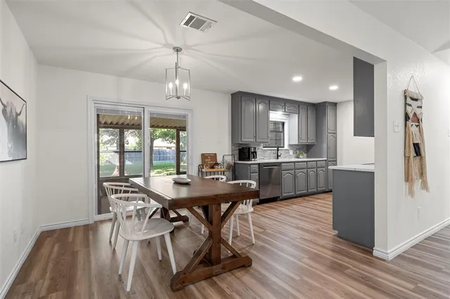 a kitchen with stainless steel appliances kitchen island granite countertop a dining table chairs and refrigerator