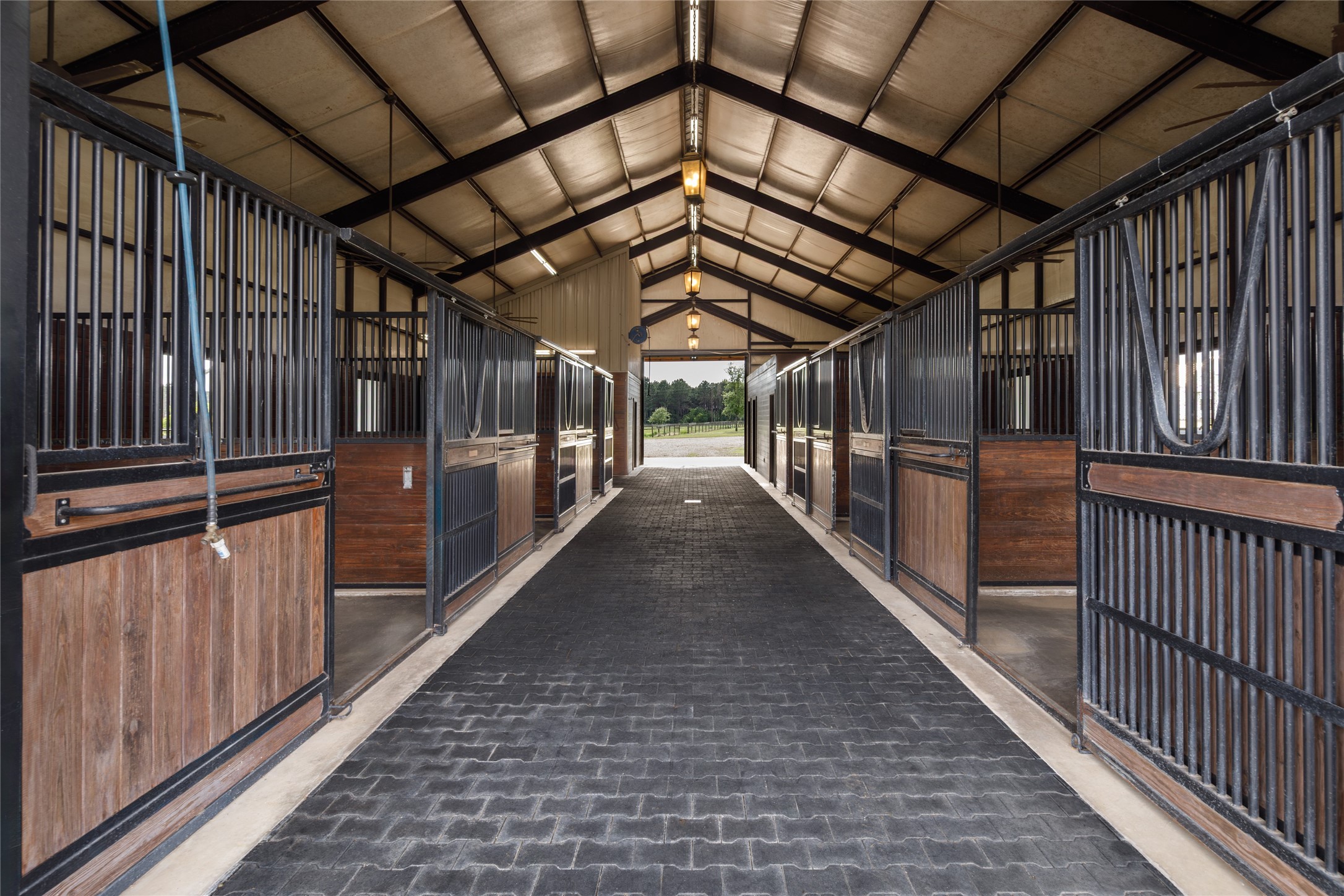 24118 Margerstadt Road Hockley, TX 77447 - Photo 5 of 49 Durable paver flooring, mounted fans, oversized stall layouts, and direct turnout access support efficient day to day equestrian operation throughout the barn. The layout was designed to balance horse comfort with long term practicality.