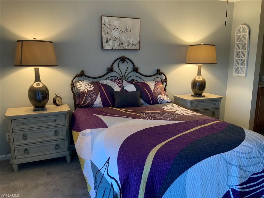 5530 Rattlesnake Hammock Road, Unit K103 Naples, FL 34112 - Photo 15 of 32 a bedroom with a bed and a lamp