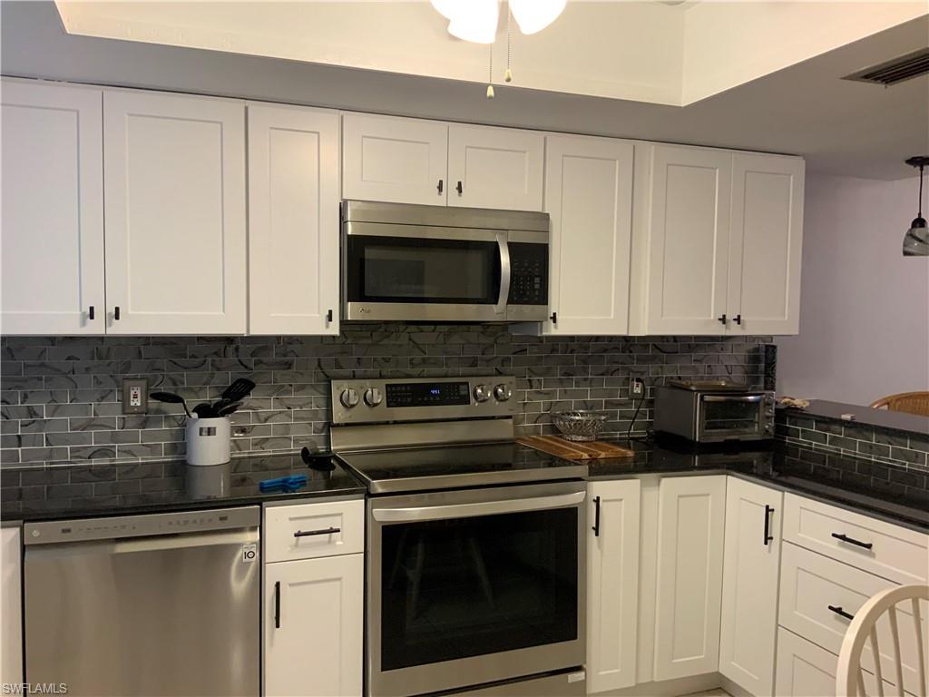 5530 Rattlesnake Hammock Road, Unit K103 Naples, FL 34112 - Photo 23 of 32 a kitchen with granite countertop white cabinets and stainless steel appliances