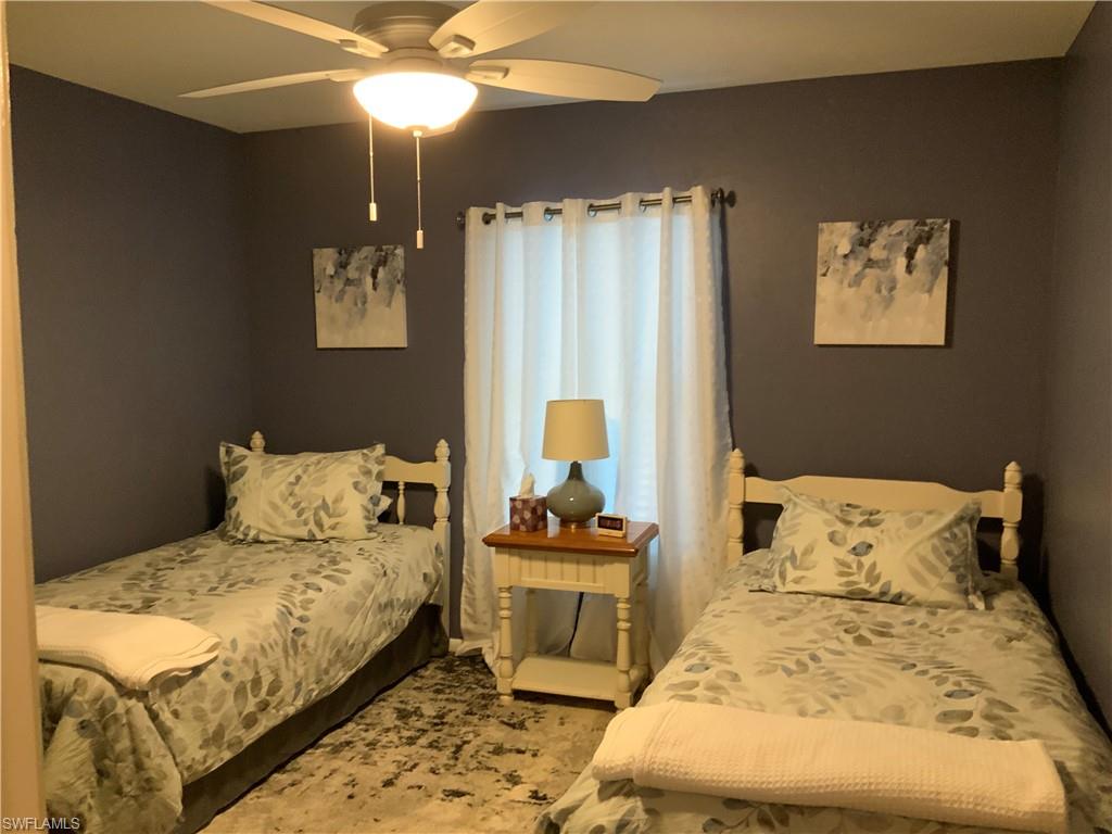 5530 Rattlesnake Hammock Road, Unit K103 Naples, FL 34112 - Photo 25 of 32 a bedroom with a bed and a chandelier