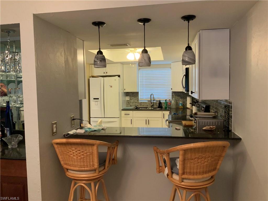 5530 Rattlesnake Hammock Road, Unit K103 Naples, FL 34112 - Photo 28 of 32 a kitchen with stainless steel appliances granite countertop a sink and cabinets