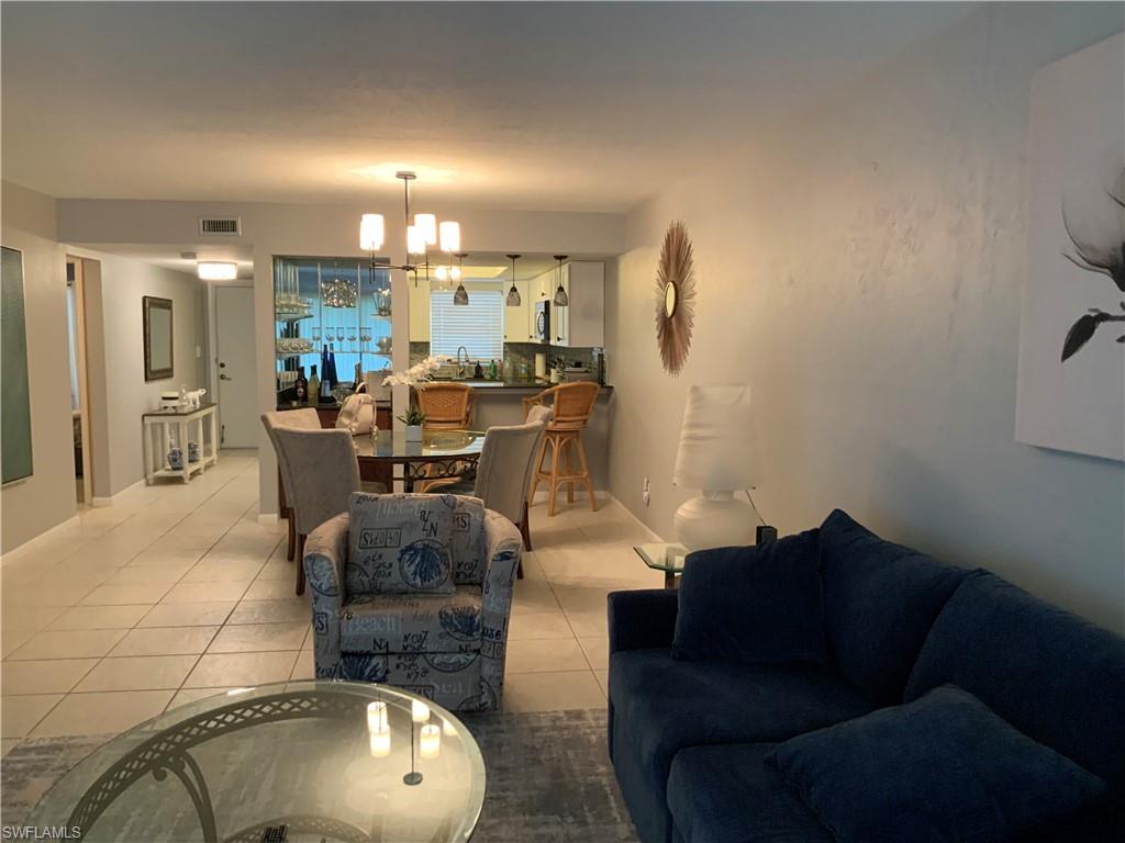 5530 Rattlesnake Hammock Road, Unit K103 Naples, FL 34112 - Photo 29 of 32 a living room with furniture and a chandelier