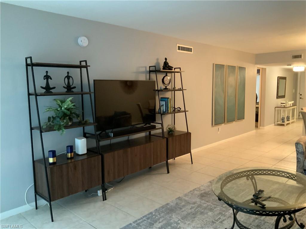 5530 Rattlesnake Hammock Road, Unit K103 Naples, FL 34112 - Photo 30 of 32 a living room with furniture and a flat screen tv