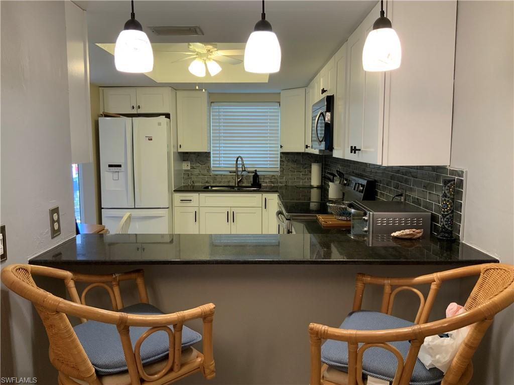5530 Rattlesnake Hammock Road, Unit K103 Naples, FL 34112 - Photo 6 of 32 a kitchen with a dining table cabinets and stainless steel appliances