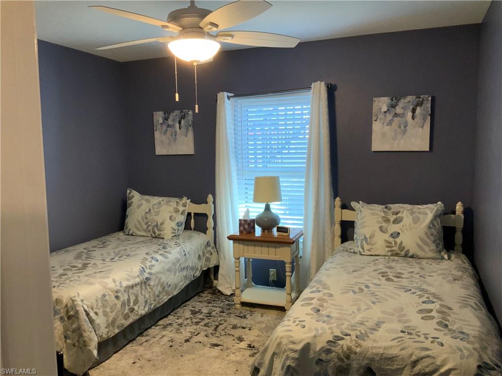 5530 Rattlesnake Hammock Road, Unit K103 Naples, FL 34112 - Photo 8 of 32 a bedroom with a bed and a chandelier