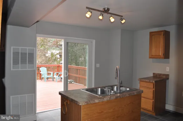 a dining room with wooden floor a chandelier fan a kitchen and windows