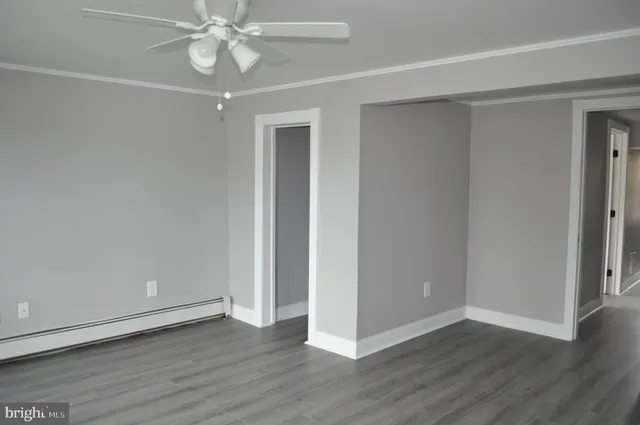 an empty room with wooden floor and fan