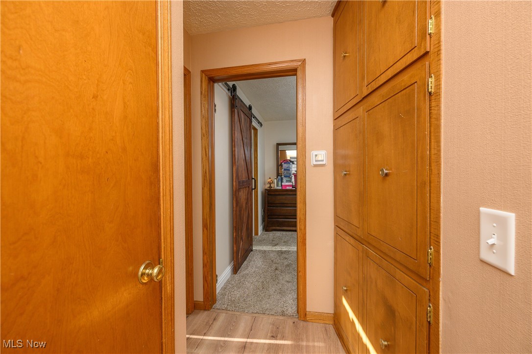1320 Perry Drive Northwest Canton, OH 44708 - Photo 19 of 34 Hall featuring a barn door, a textured ceiling, and light hardwood / wood-style floors
