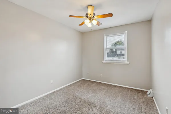 an empty room with a window and ceiling fan