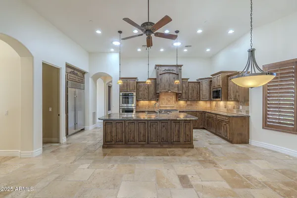a large kitchen with a large counter top a sink stainless steel appliances and cabinets