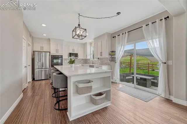 a kitchen with granite countertop a sink cabinets stainless steel appliances and a window