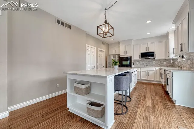 a open kitchen with stainless steel appliances granite countertop a dining table chairs and window