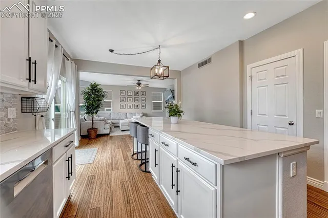 an empty room with wooden floor cabinet and windows