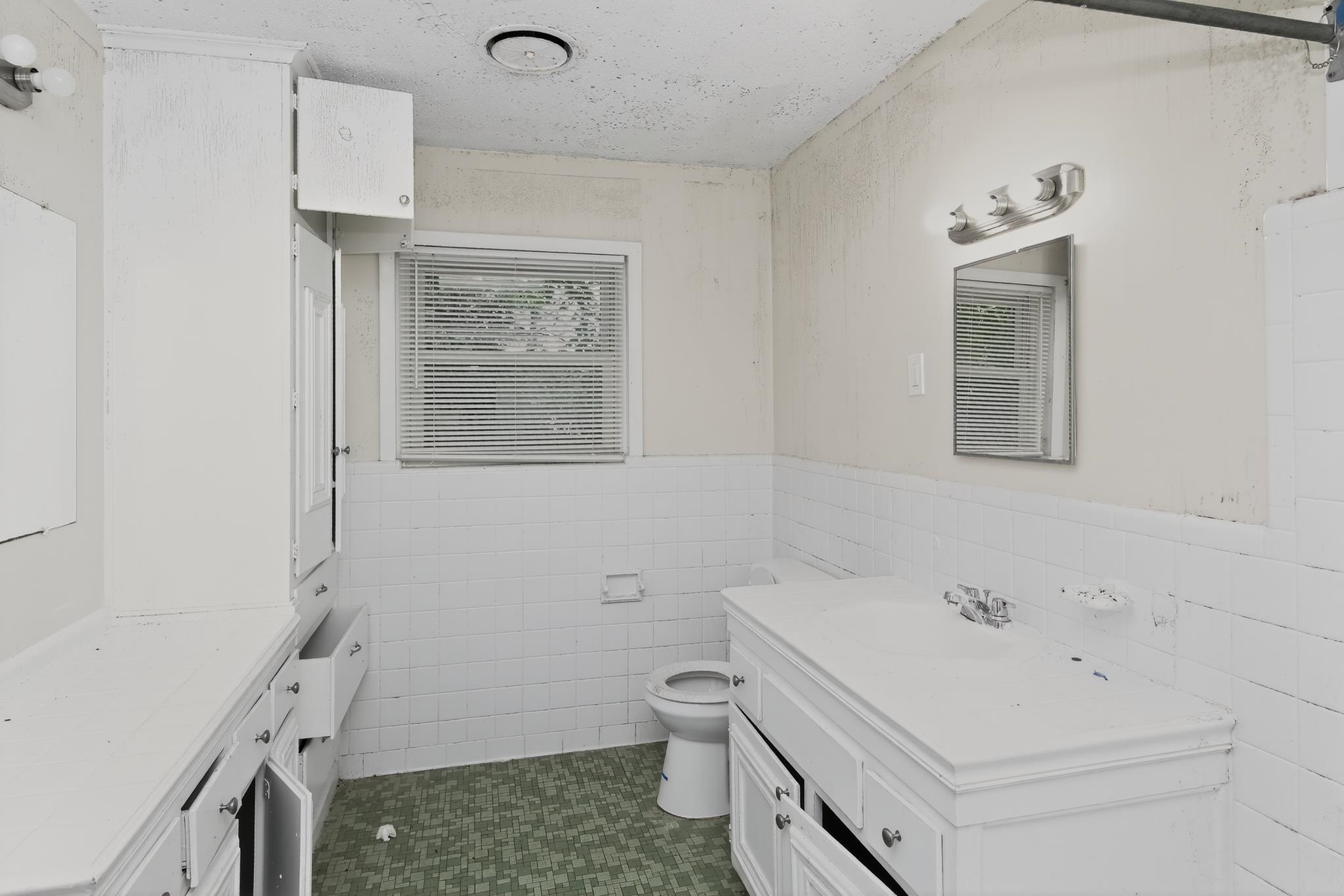 1403 Old Hickory Road Memphis, TN 38116 - Photo 26 of 31 Bathroom featuring white tile wainscoting, green patterned floor tiling, and a window with horizontal blinds