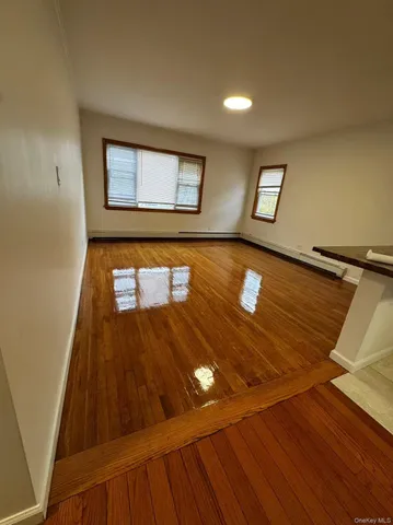 a view of an empty room with window and wooden floor