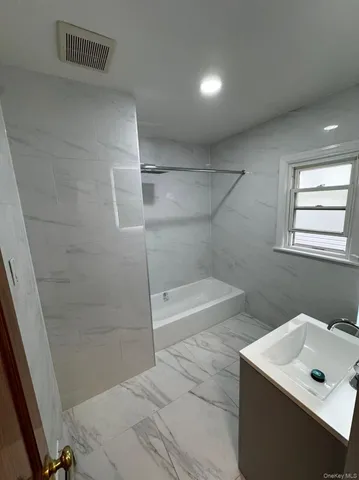 a bathroom with a bathtub sink vanity and mirror