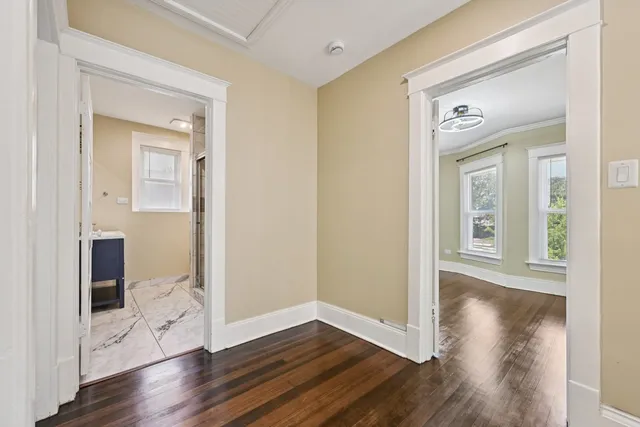 a view of a hallway with wooden floor and a bathroom