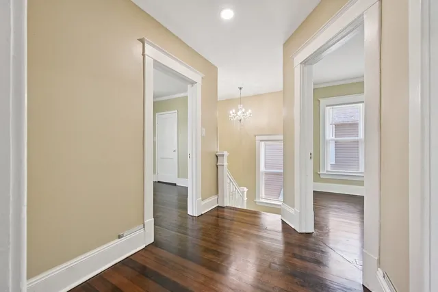 a view of an empty room with wooden floor and a bathroom